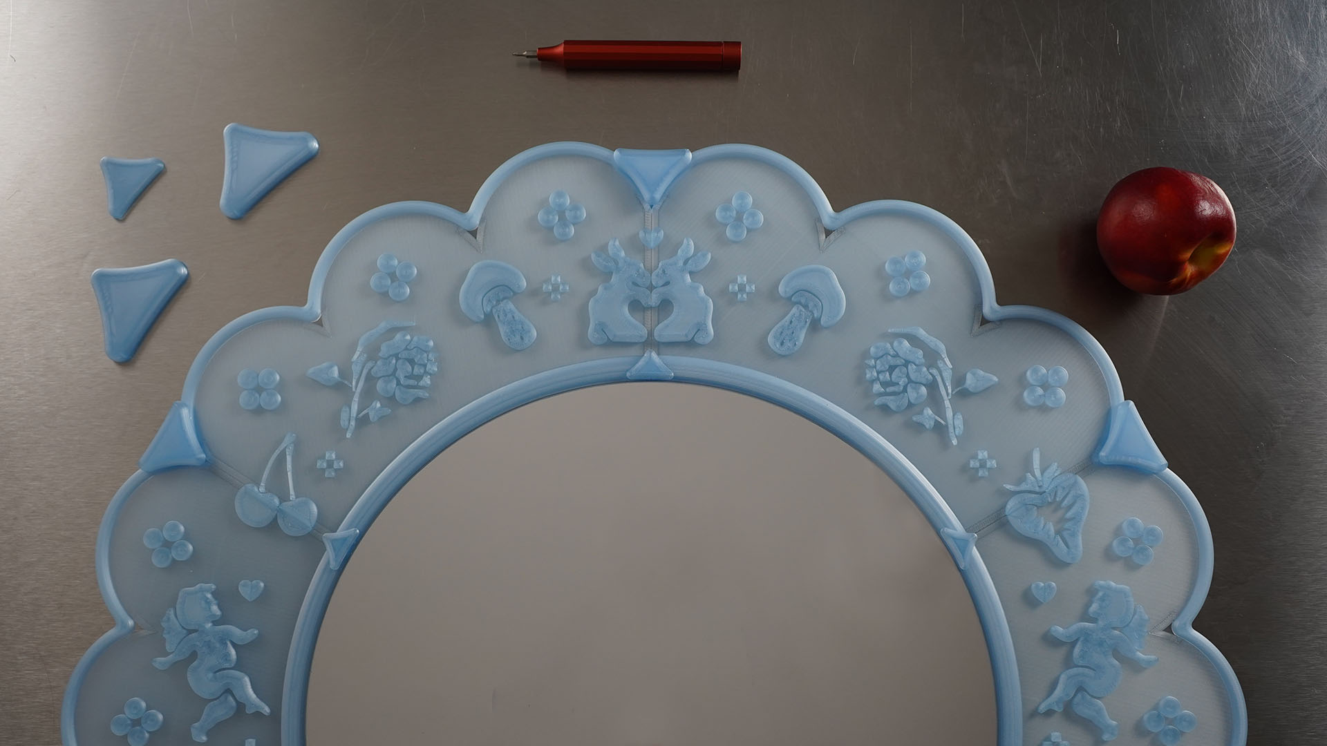 A translucent blue 3D lace mirror prototype on a brushed metal work surface.